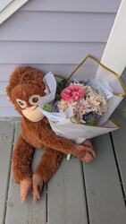 A plush monkey holding a fresh floral bouquet outside The Lavender House in Edmonton